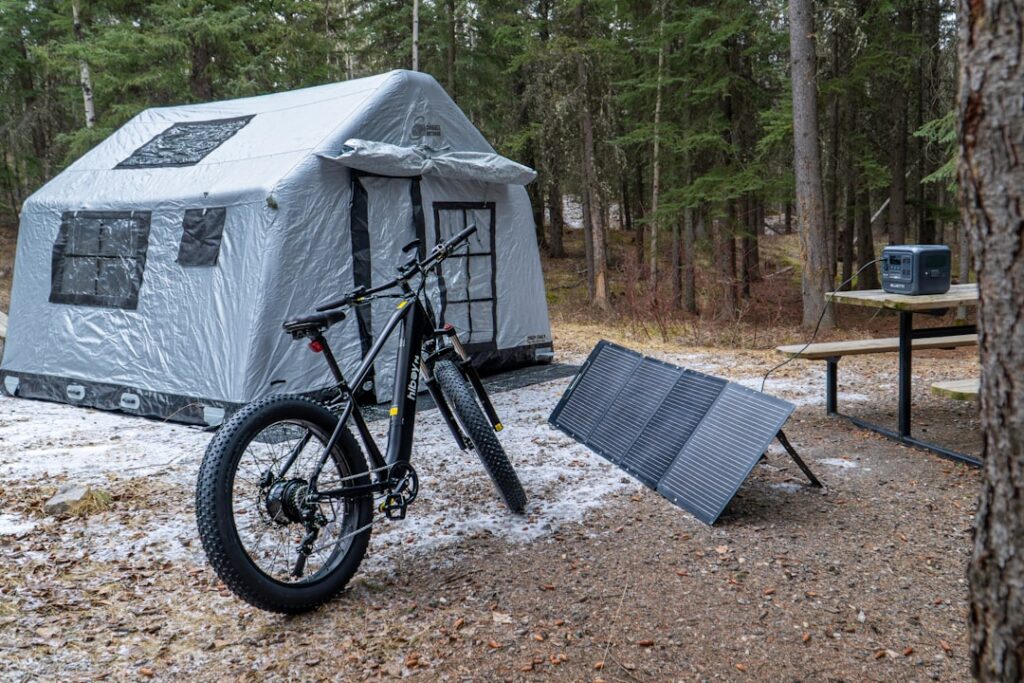 Inflatable tent with bicycle and solar panel at campsite.